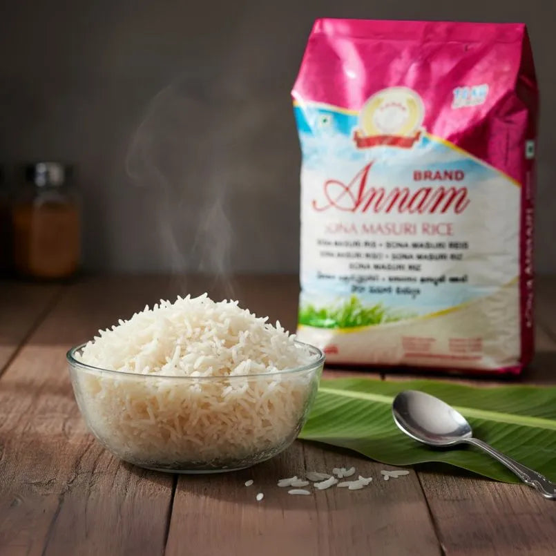 Bowl of steaming rice with a packet of Annam Sona Masuri Rice on a wooden surface.