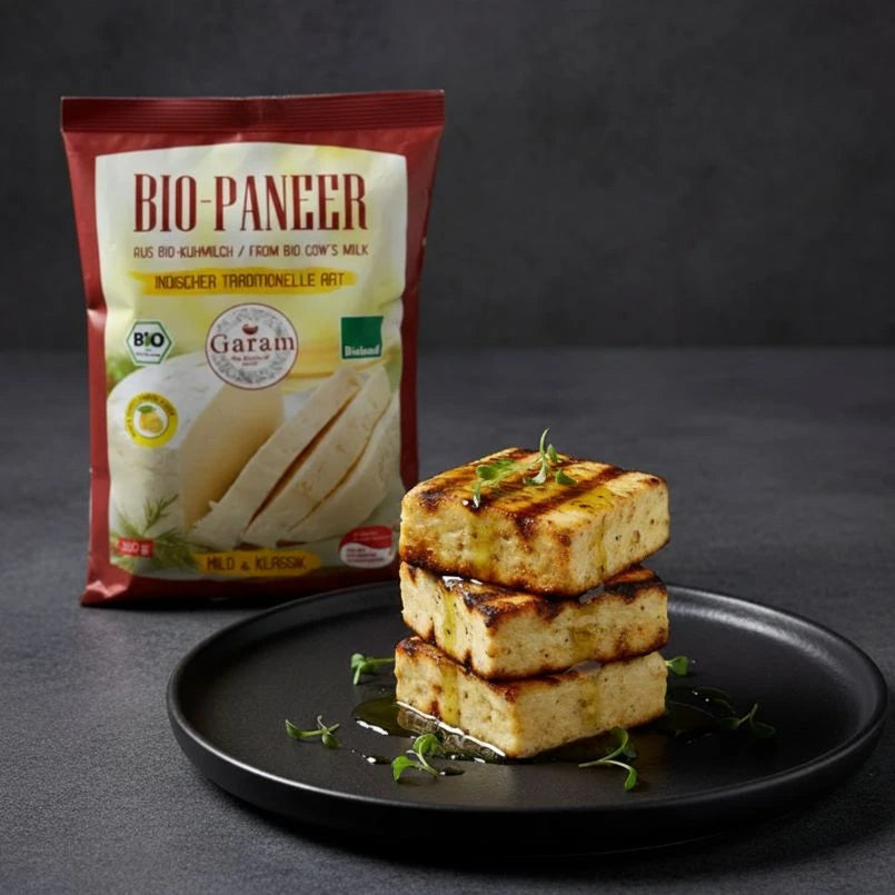 Bio Paneer packaging with a stack of paneer cubes on a black plate against a dark background