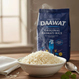 Bowl of steaming rice with a bag of DAAWAT Original Basmati Rice in the background.