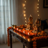 Decorative table with statues, candles, and marigold flowers in a warm indoor setting.