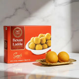 Box of Besan Laddu sweets with two laddus on a marble surface