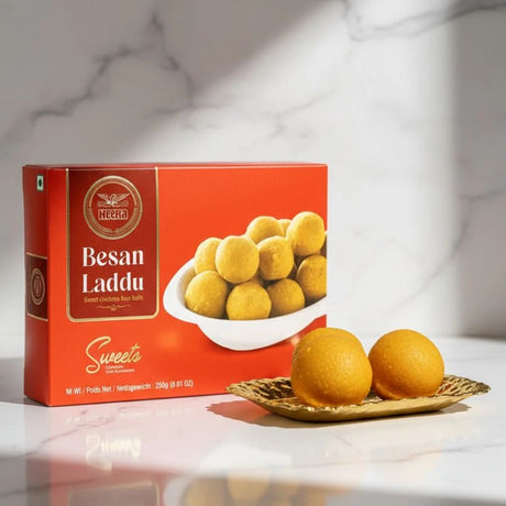 Box of Besan Laddu sweets with two laddus on a marble surface