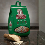 Green bag of India Gate Kaima Rice with a scoop of rice on a dark surface