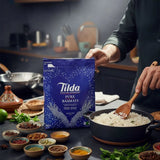 Person cooking rice with a Tilda Pure Basmati rice bag in a kitchen setting
